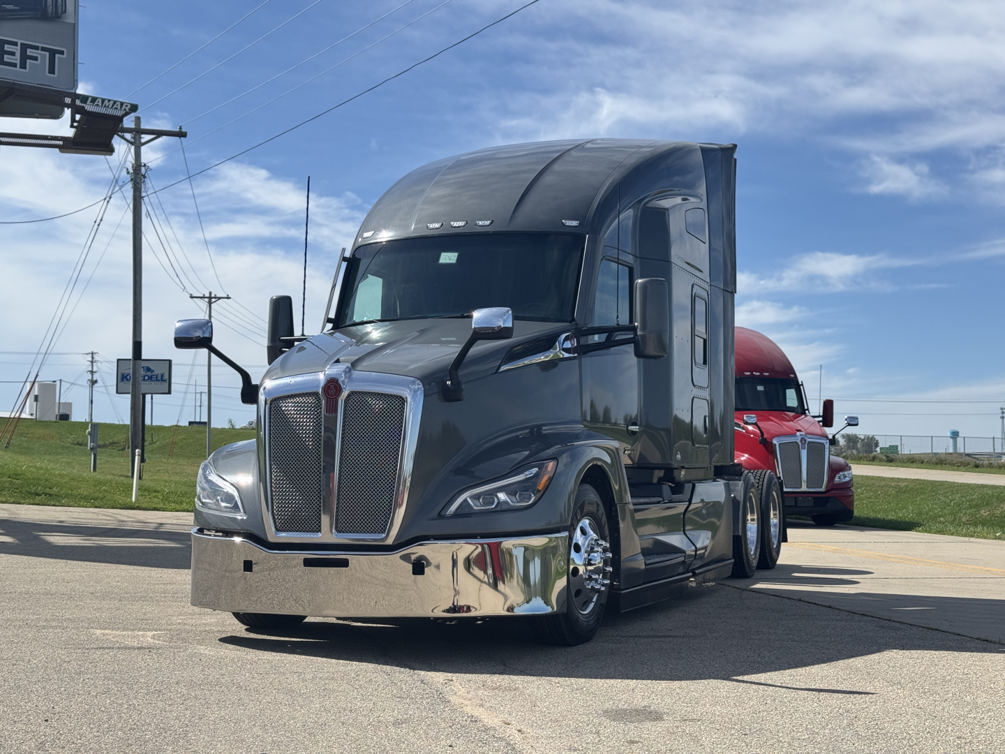 Kenworth T680 conventional sleeper truck in dark gray, front view, chrome bumper, large grille, mirrors, and aerodynamic hood.