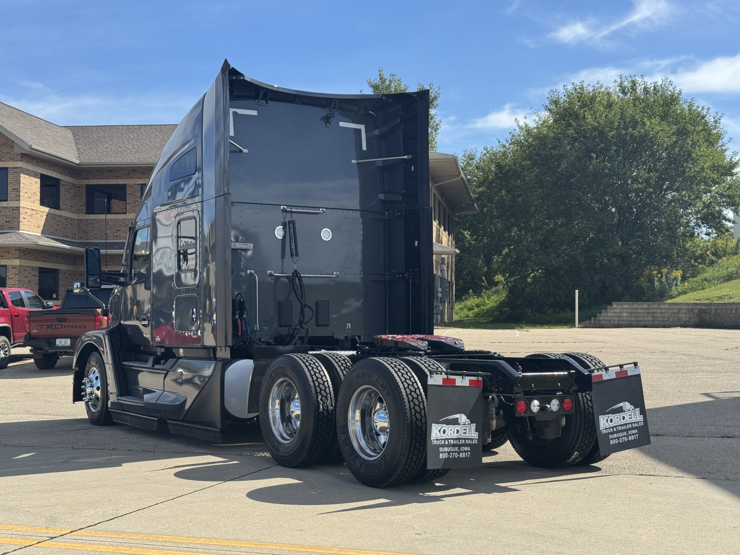 Kenworth T680 semi-truck tractor rear and side view showing triple rear axles with chrome wheels and black sleeper cab.