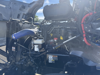 Kenworth T680 engine bay showing coolant reservoir, hoses, and engine components with wiring harnesses and labels.