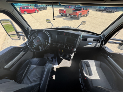 Cab interior of a 2024 Kenworth T680 showing steering wheel, dashboard, and seats with clear view of instrument panel and center stack.