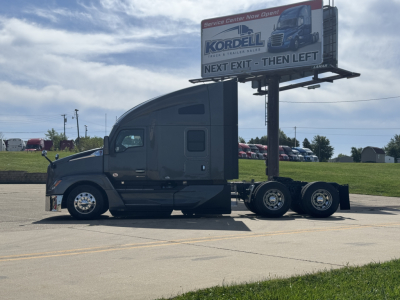 Kenworth T680 tractor in side profile showing cab and rear axles, billboard sign on trailer hitch, no trailer attached.