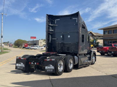 Kenworth T680 truck rear view showing sleeper cab and dual rear axles with black paint and chrome wheels.
