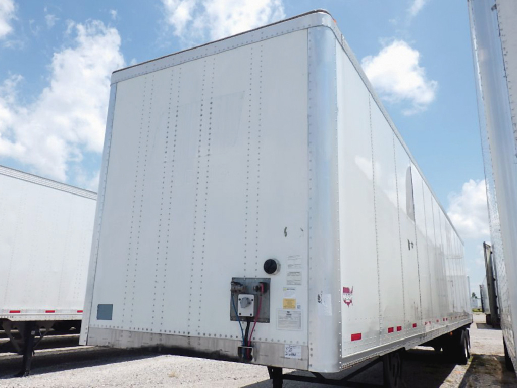 Trailer side view showing a 2021 Wabash DuraPlate cargo trailer with white aluminum exterior, front control box, and riveted panels.