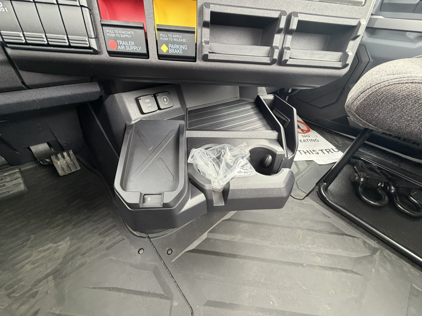 Cab area of a 2026 Mack AN64T with open storage shelf, cup holder, and dashboard switches visible.