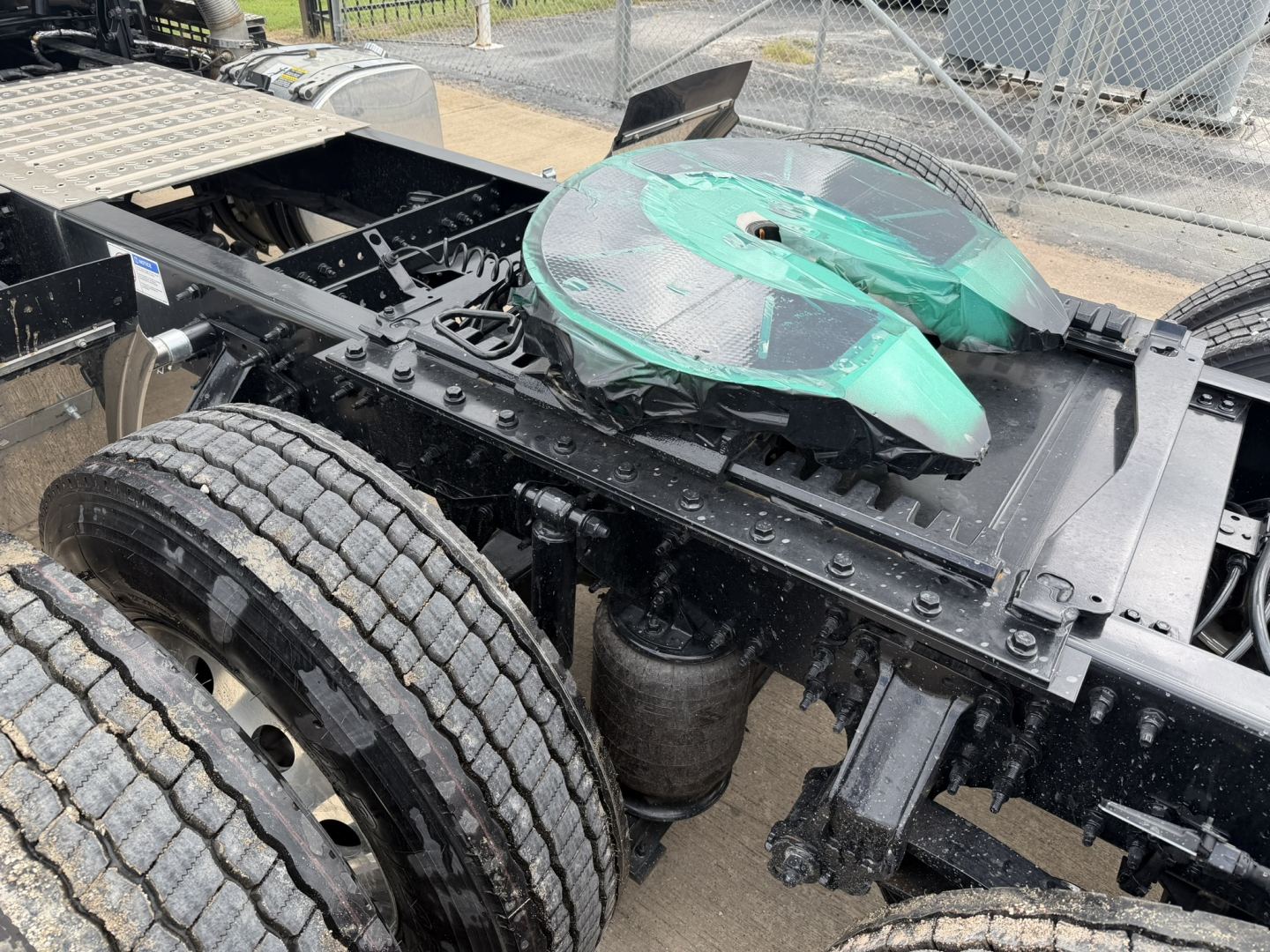 Mack AN64T chassis with green circular fuel/air reservoir cover and dual rear wheels, visible frame rails and suspension components.
