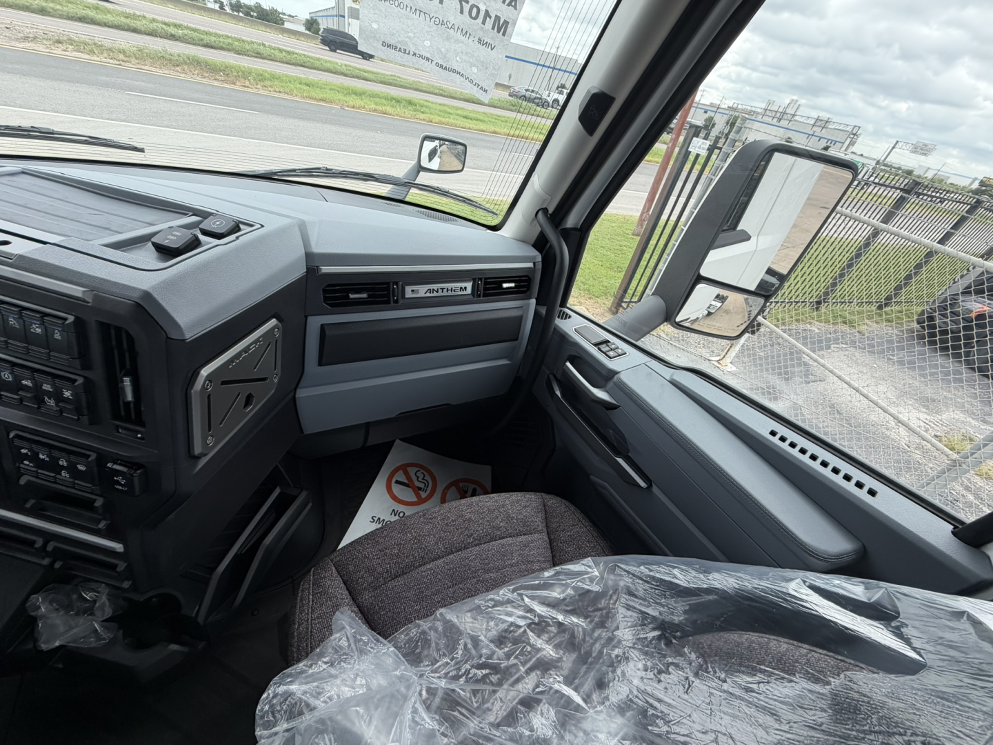 Mack AN64T truck cab interior view showing steering wheel, dashboard, and driver's seat with plastic cover.