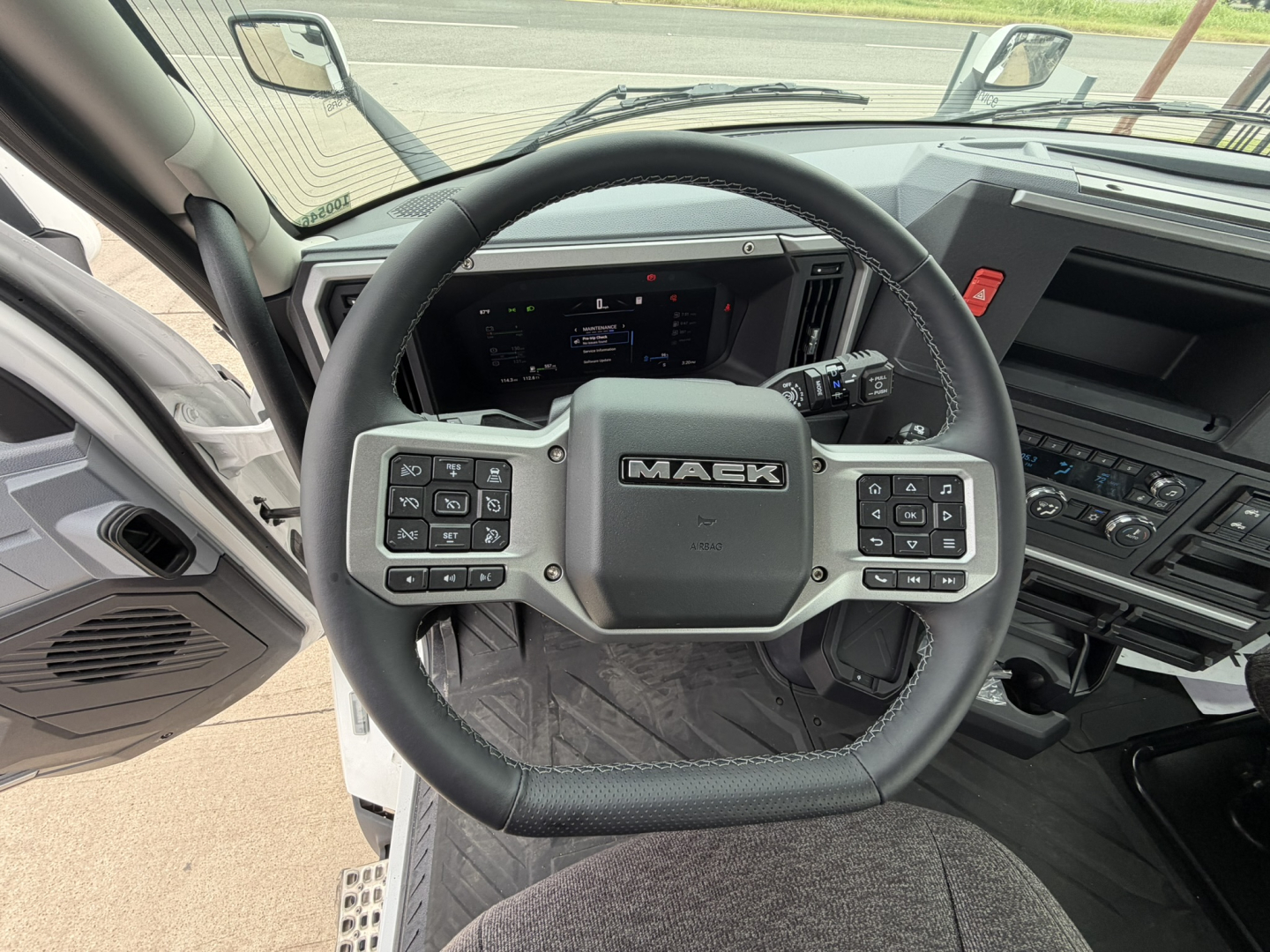 Steering wheel inside Mack AN64T cab with dashboard display; visible buttons on steering wheel and center console.