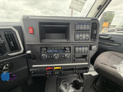 Truck cockpit dash with controls and gauges in a Mack AN64T daycab interior showing switches, climate controls, and storage dash components.