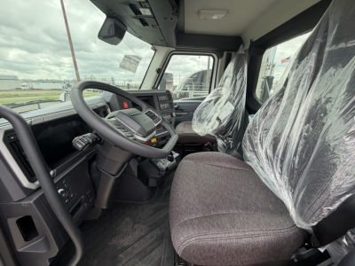 Mack AN64T truck interior view with steering wheel, dashboard, and plastic-covered seats.