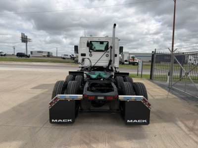 Mack AN64T truck rear view showing black mud flaps with 'MACK' text, rear chassis, and fifth wheel area, on a concrete lot.