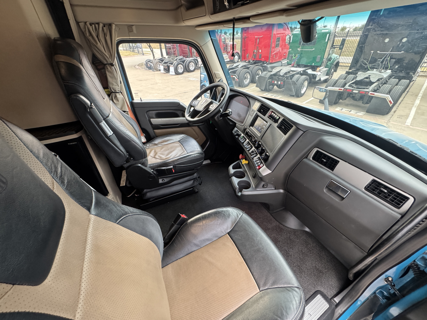 Truck cab interior of a Kenworth T680 showing driver seat and dashboard with steering wheel and controls.