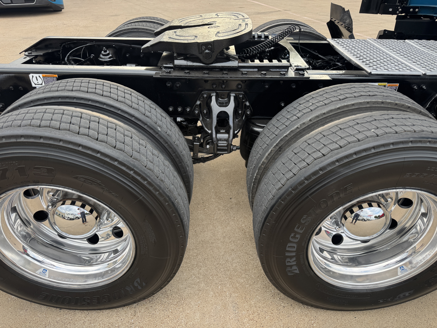 Kenworth T680 chassis with dual rear axles and polished chrome wheels; view of rear bogie, fifth wheel and mounting hardware visible.