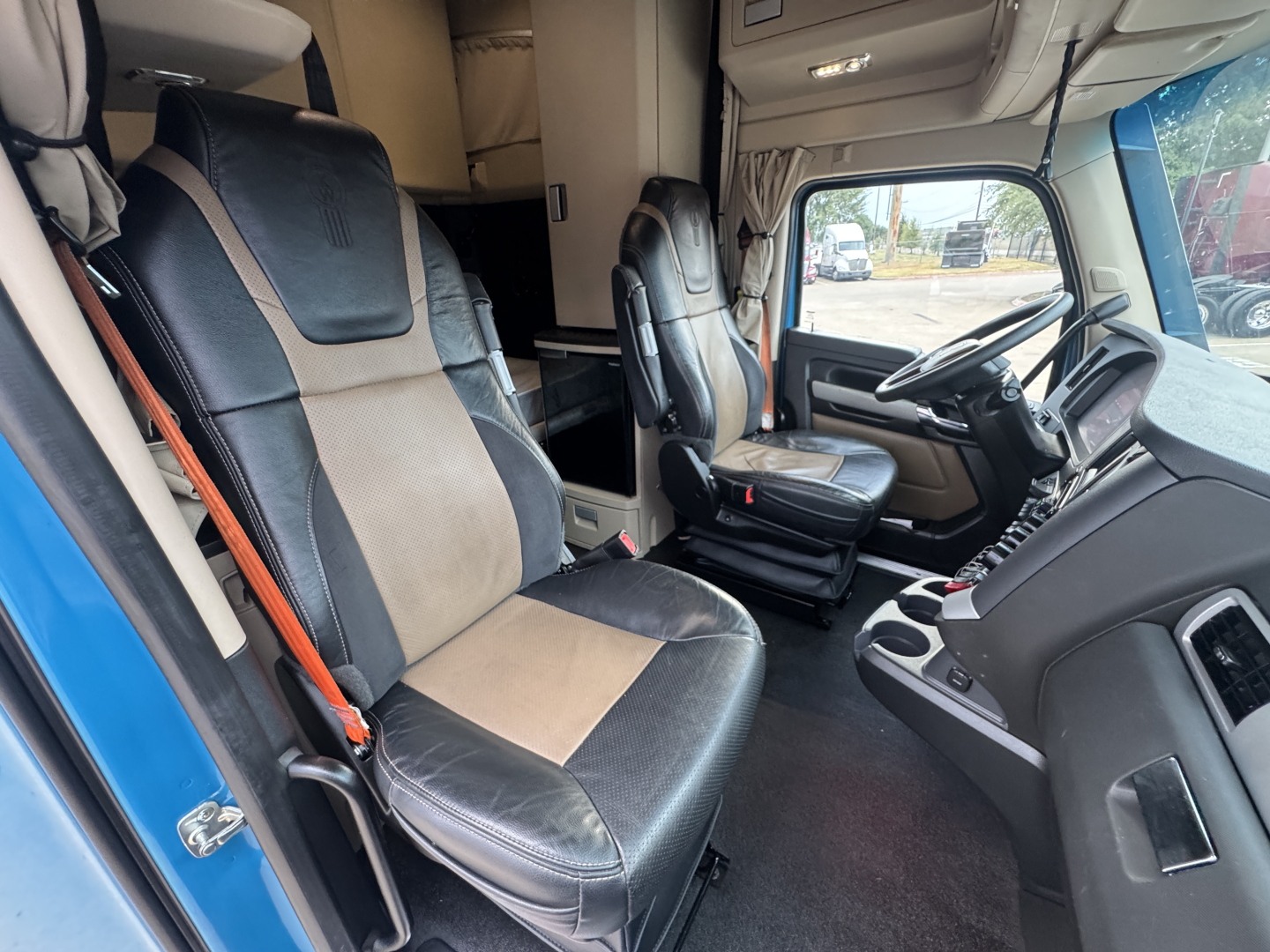Truck interior cab with two front seats, steering wheel, and dashboard; visible text on screen and controls not legible.