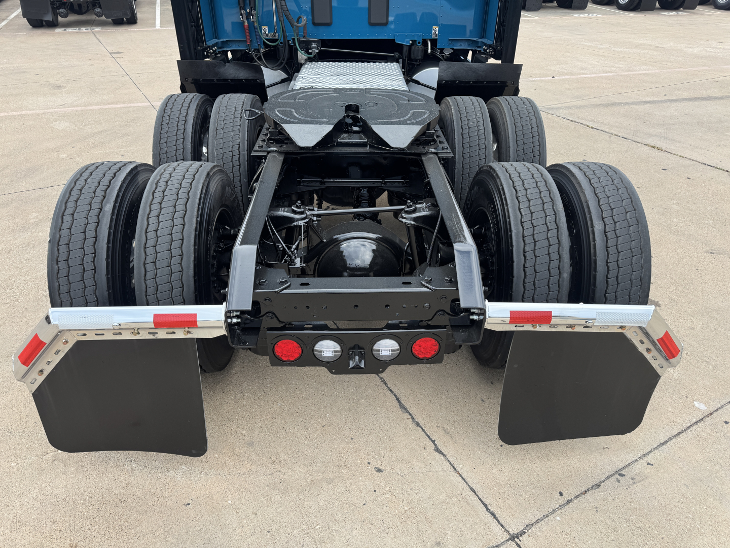 Kenworth T680 rear view showing dual rear axle, drive tires, fifth wheel, and mud flaps.