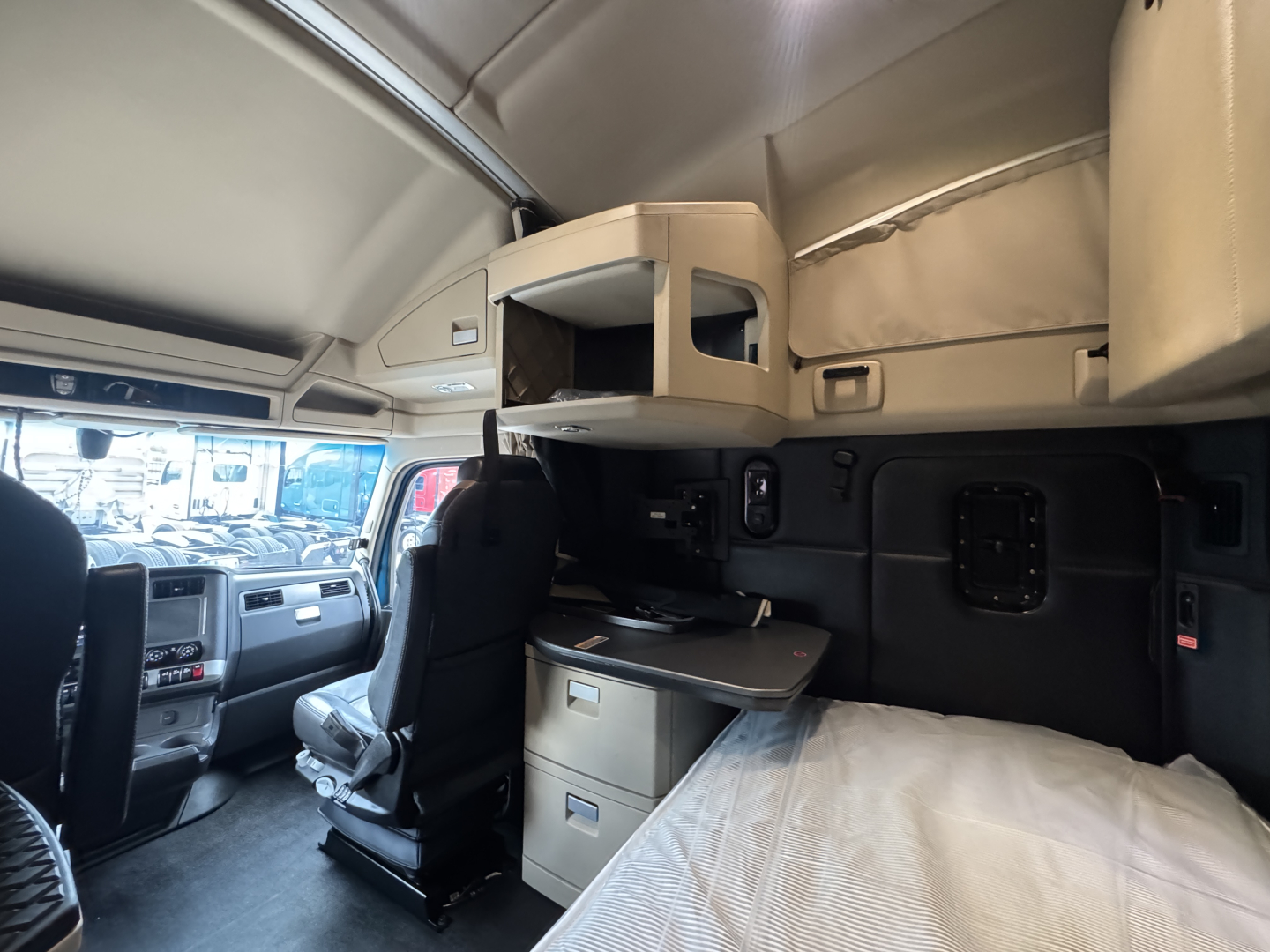 Kenworth T680 sleeper cab interior with upper storage shelf, desk area, and bed visible.