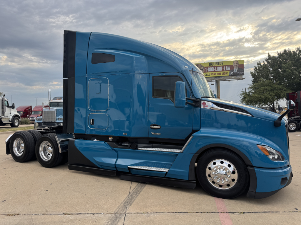 Kenworth T680 sleeper cab truck side profile showing blue exterior, chrome wheels, aerodynamic mirrors, and dual rear axles.