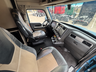 Truck cab interior of a Kenworth T680 showing driver seat and dashboard with steering wheel and controls.