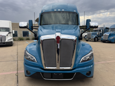 Front view of a blue 2024 Kenworth T680 sleeper cab truck showing large chrome grille, headlamps, and Kenworth emblem.