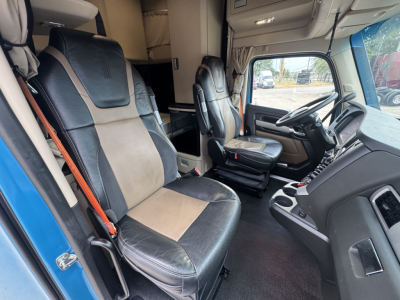 Truck interior cab with two front seats, steering wheel, and dashboard; visible text on screen and controls not legible.