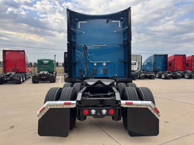 Kenworth T680 rear view showing blue sleeper cab, dual rear axles, and large mud flaps with chassis hitch area visible.