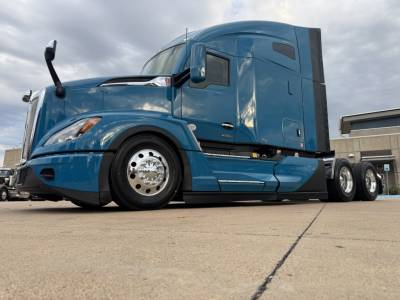Kenworth T680 tractor shown from low-angle side view in blue with sleeper cab and chrome wheels.
