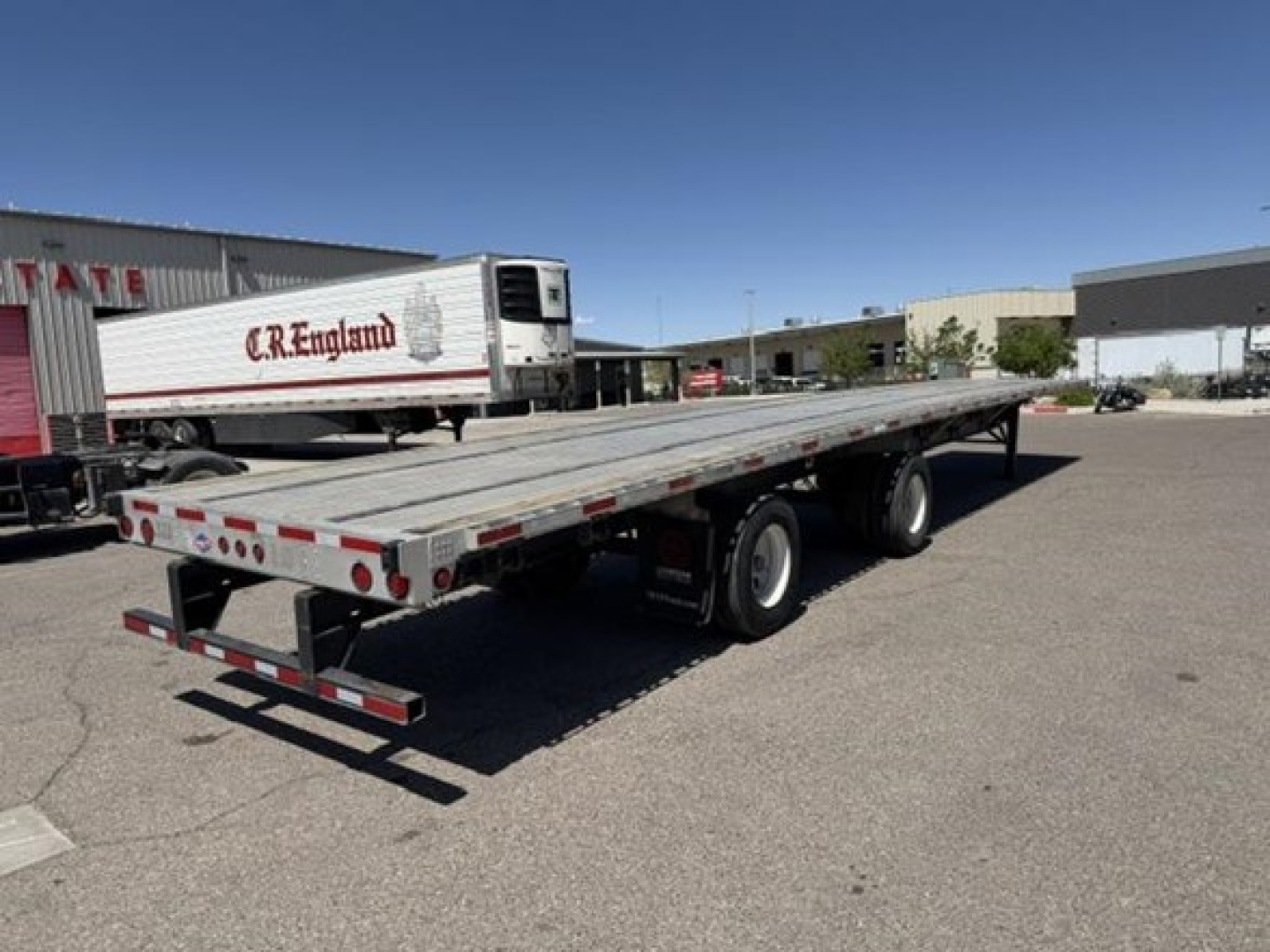 Flatbed trailer with air ride combo showing long aluminum deck and tandem axles.