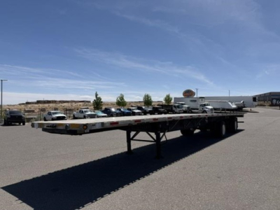 Flatbed trailer with air ride combo showing long deck and support legs in a parking lot.