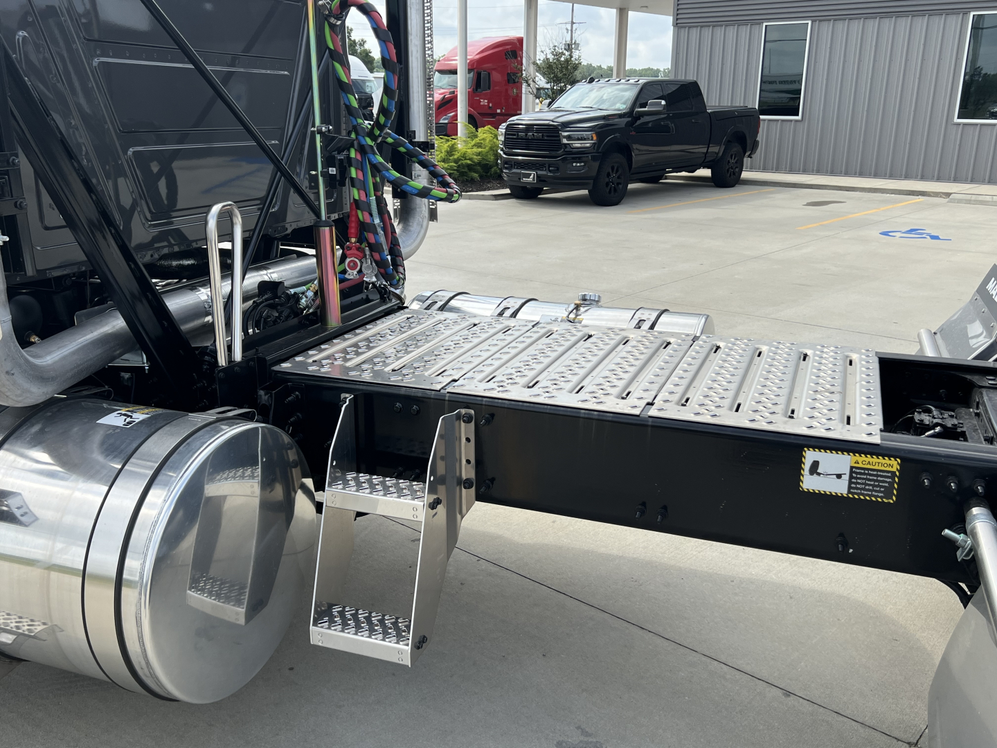 Truck chassis and steps with metal platform, fuel tank, and plumbing lines visible. No readable model-specific text on the image; generic industrial truck components visible.