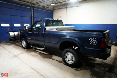 Ford F-250 Super Duty XL pickup truck with plow and toolbox in a workshop.