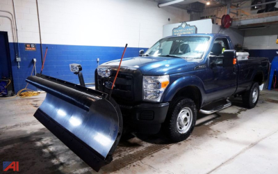Ford F-250 Super Duty XL pickup truck in a garage with a large plow attachment in front.