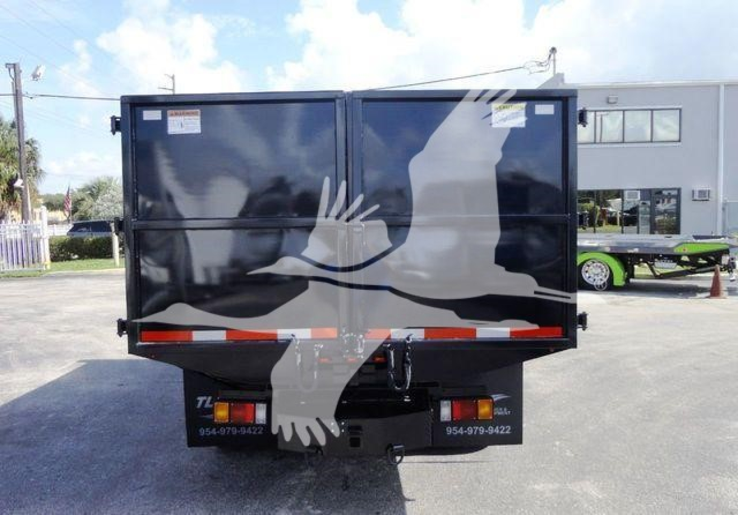 Isuzu NPR HD dump truck rear view showing dual rear doors with warning labels and a folded tailgate.