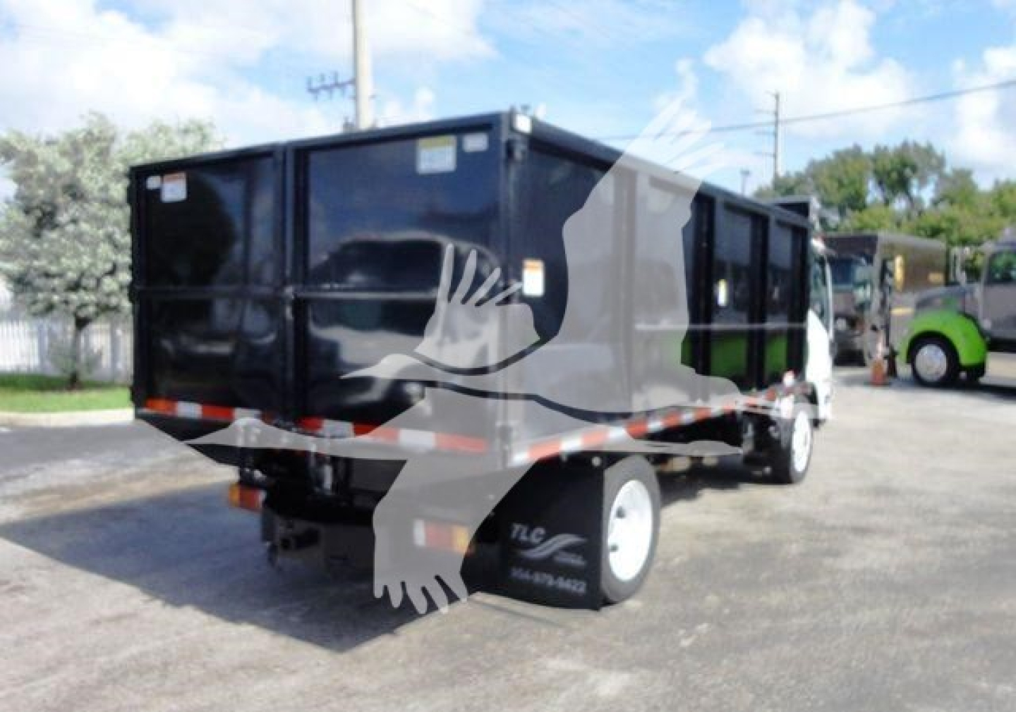 Isuzu NPR HD dump truck rear left view showing cargo bed and chassis with black container