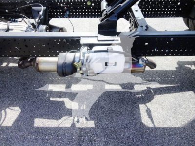 Isuzu NPR-HD truck chassis showing drivetrain underframe and differential with exhaust/muffler visible.
