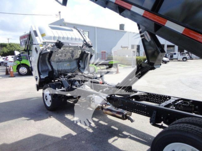 Isuzu NPR HD dump truck chassis with cab tilted forward exposing engine bay and frame, front axle, and hydraulic components.
