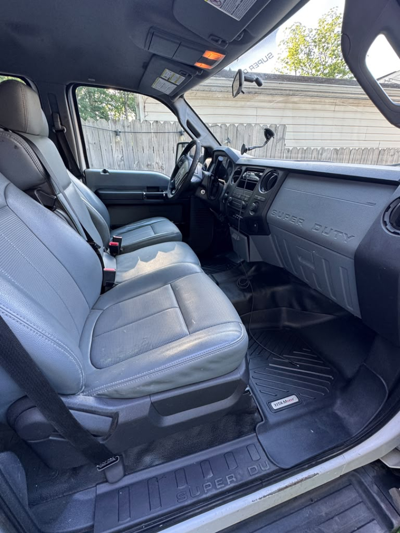Ford F-550 truck interior with gray cloth seats and dashboard; front door open, showing Ford Super Duty floor mats.