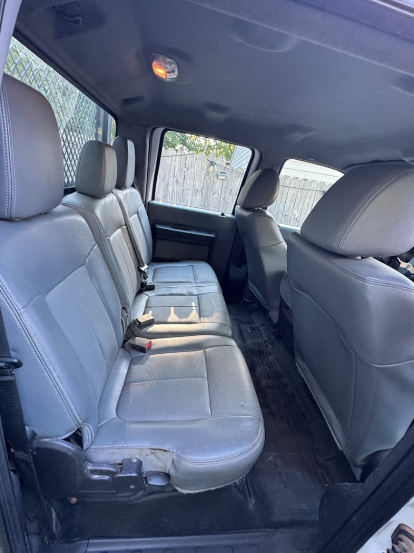 Ford F-550 interior rear seating area with gray fabric seats, three-row bench, black rubber floor mat, headrests, and door panels visible.