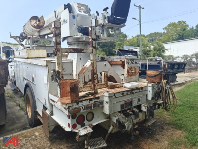Truck bed with service crane and equipment rack, rear view of a 2008 Ford F-750 bucket truck showing rusty metal brackets and work platform.