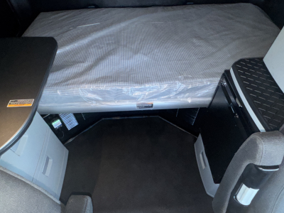 Kenworth T680 sleeper cab interior with folded mattress and storage compartments visible.