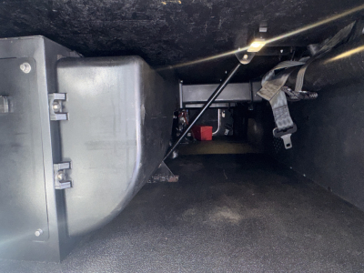 Under-dash area of a Kenworth T680 showing exposed wiring and a rectangular metal component; no legible labels visible.