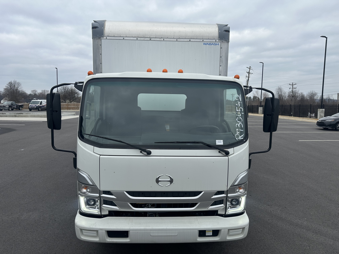 Front view of a white 2024 Hino S5 box truck with large side mirrors and orange clearance lights, VIN plate and stock number not visible.