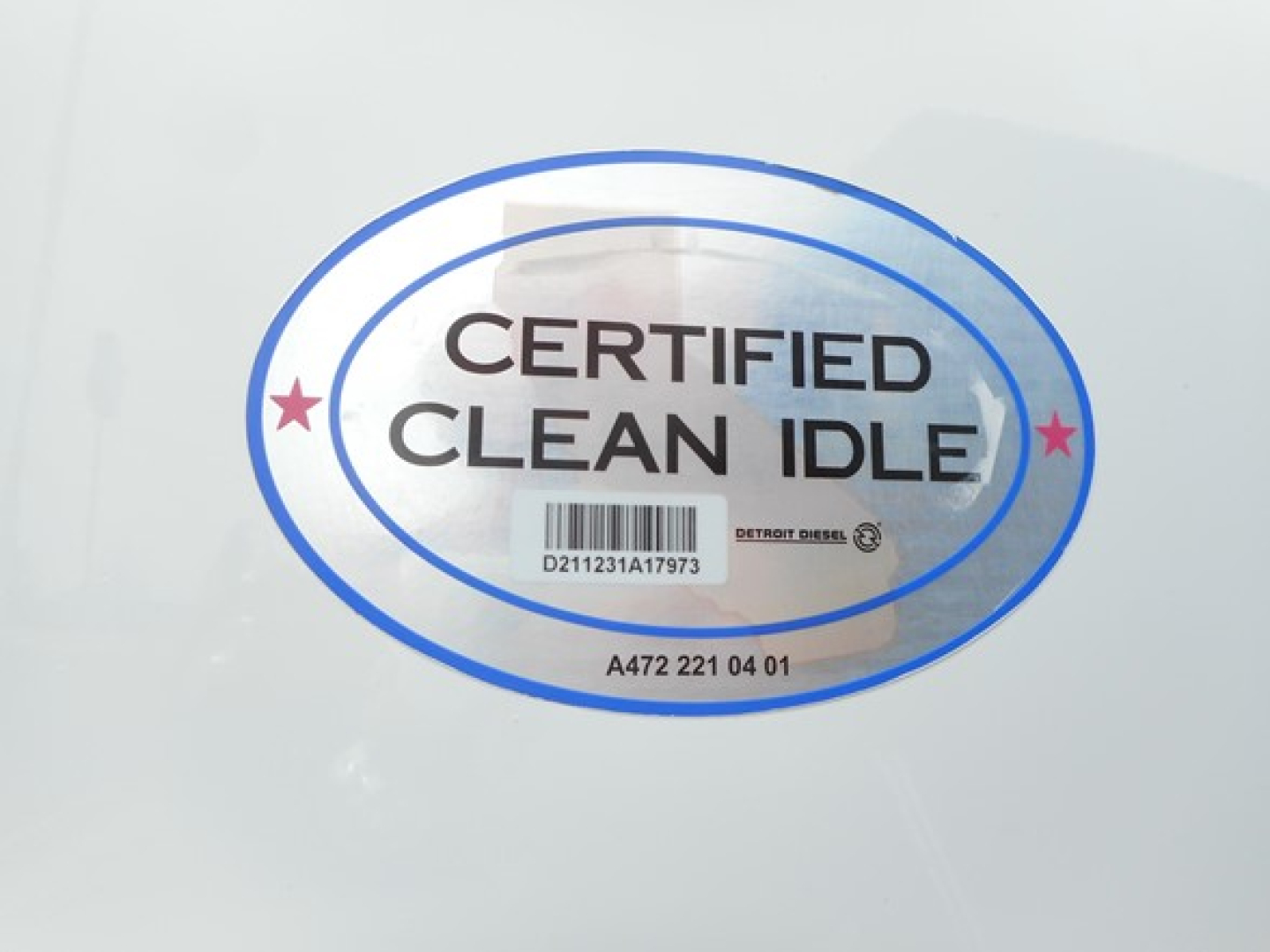 Certified Clean Idle sticker on Freightliner truck showing blue oval with barcode and text.