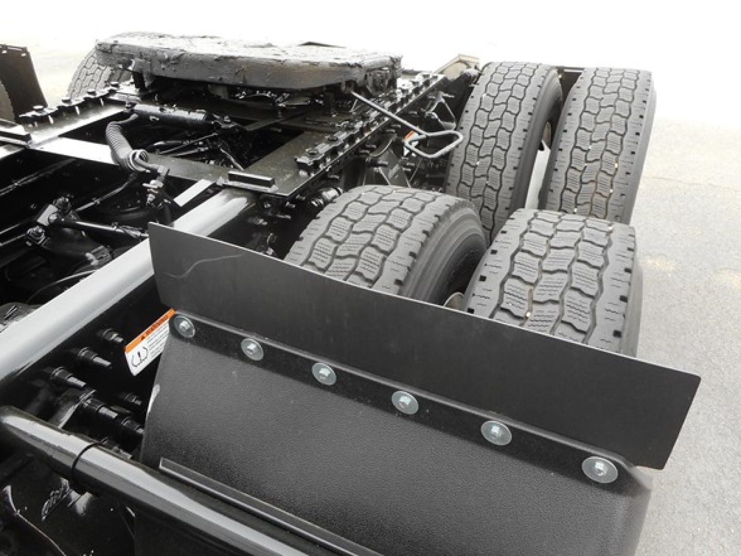 Freightliner Cascadia 126 truck chassis view showing tandem rear axles and mounting rails, with a flatbed-style skid plate and suspension components visible.