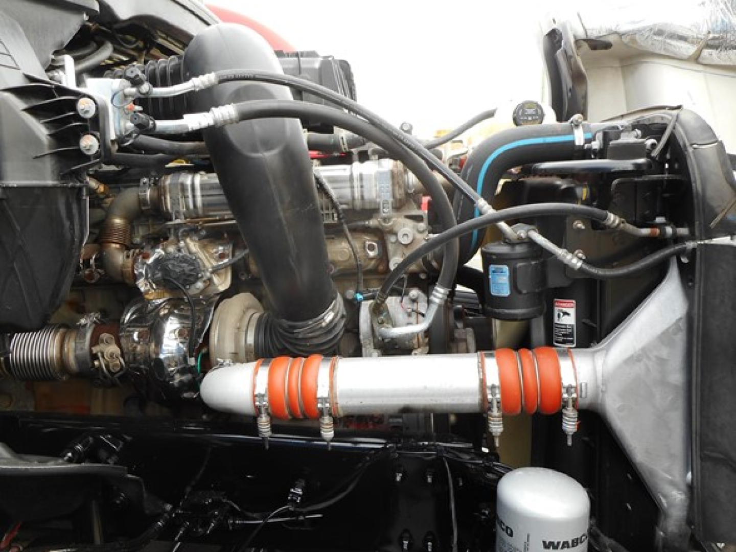 Engine bay of a 2023 Freightliner Cascadia 126 showing hoses, intercooler piping, and auxiliary components.