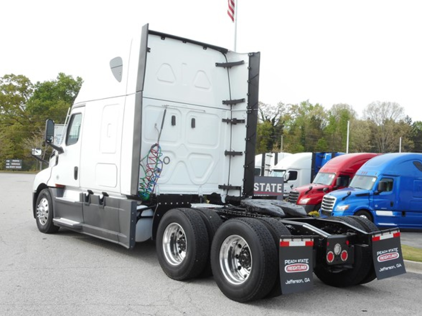 Freightliner Cascadia 126 tractor rear and cab side showing 6-wheel rear axle, white exterior, trailer connection area, no visible text on doors.