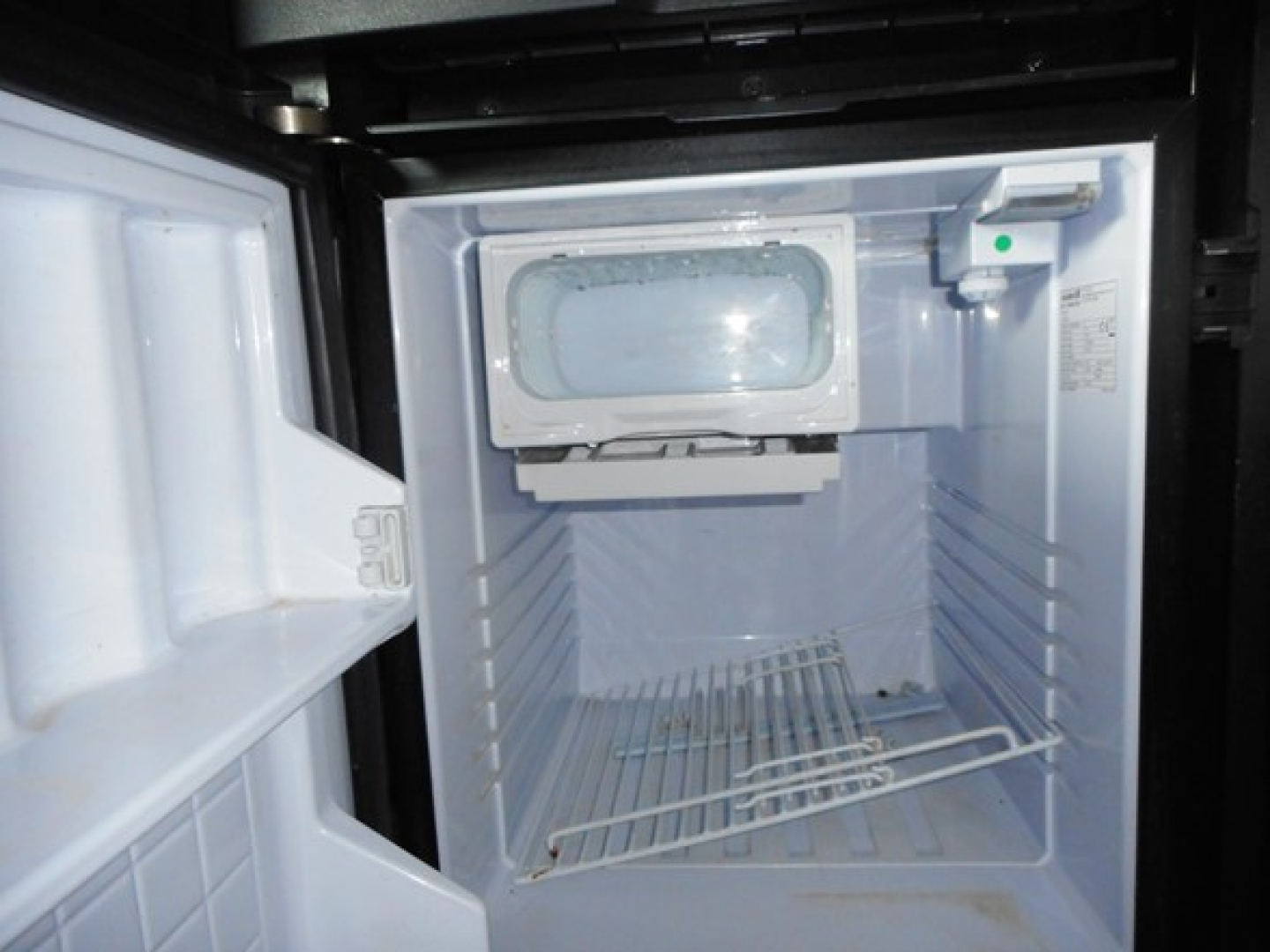 Freightliner Cascadia 126 engine bay showing empty refrigerator compartment? No, it's a small freezer or storage unit inside the sleeper with open door.