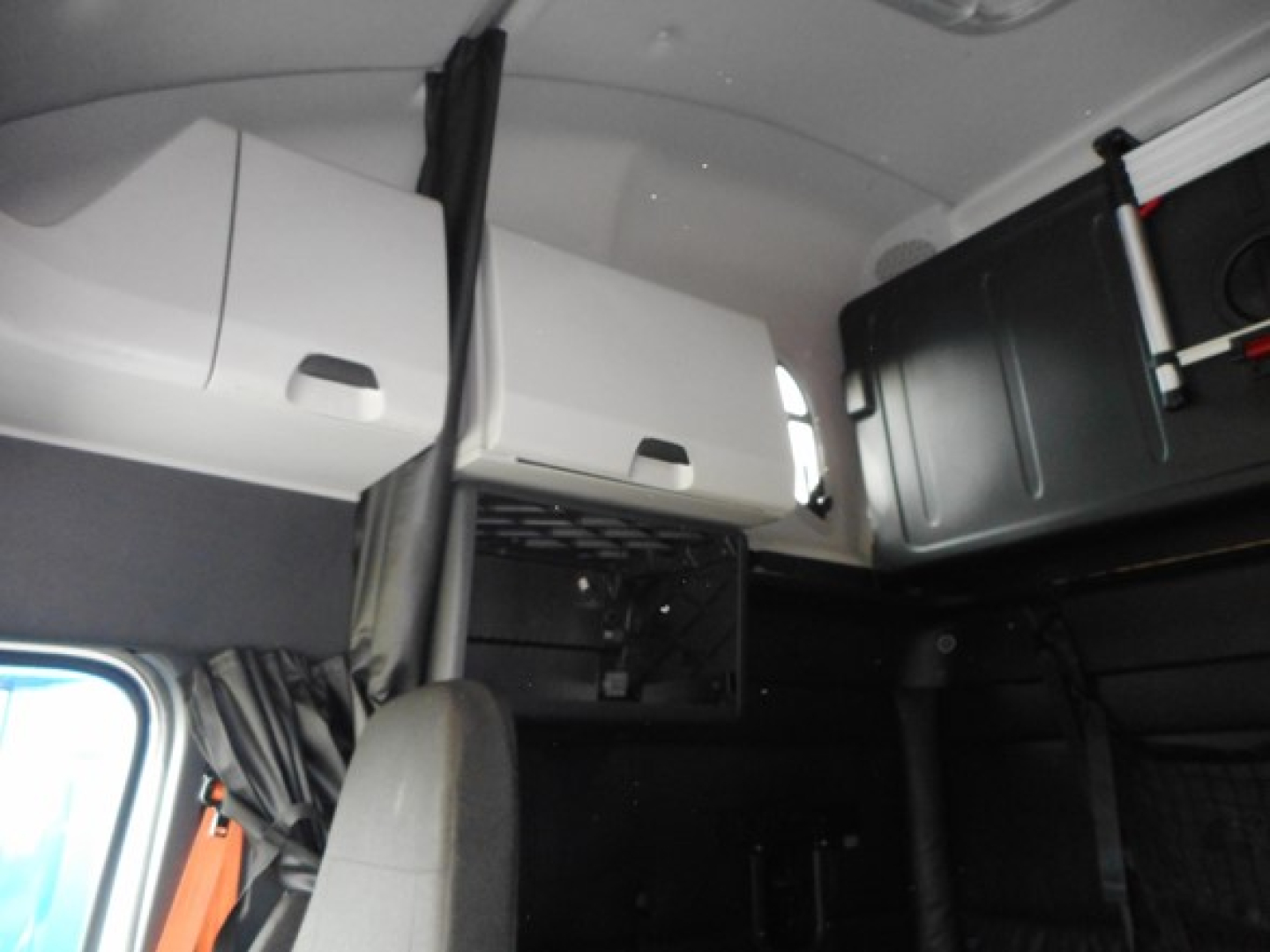 Freightliner Cascadia truck cab interior showing overhead storage compartments and sleeping area.