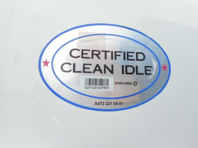 Certified Clean Idle sticker on Freightliner truck showing blue oval with barcode and text.