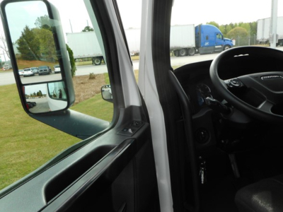 Cab interior and driver-side door area of a Freightliner Cascadia 126 truck showing steering wheel, dashboard, and side mirror.