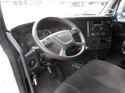 Truck cab interior showing steering wheel and dashboard of a Freightliner Cascadia 126 sleeper, with instrument cluster and center console controls.