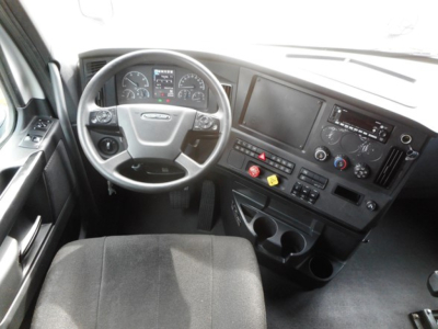 Cab interior of a 2023 Freightliner Cascadia 126 showing steering wheel, dashboard, gauges, large central display, and control panel.